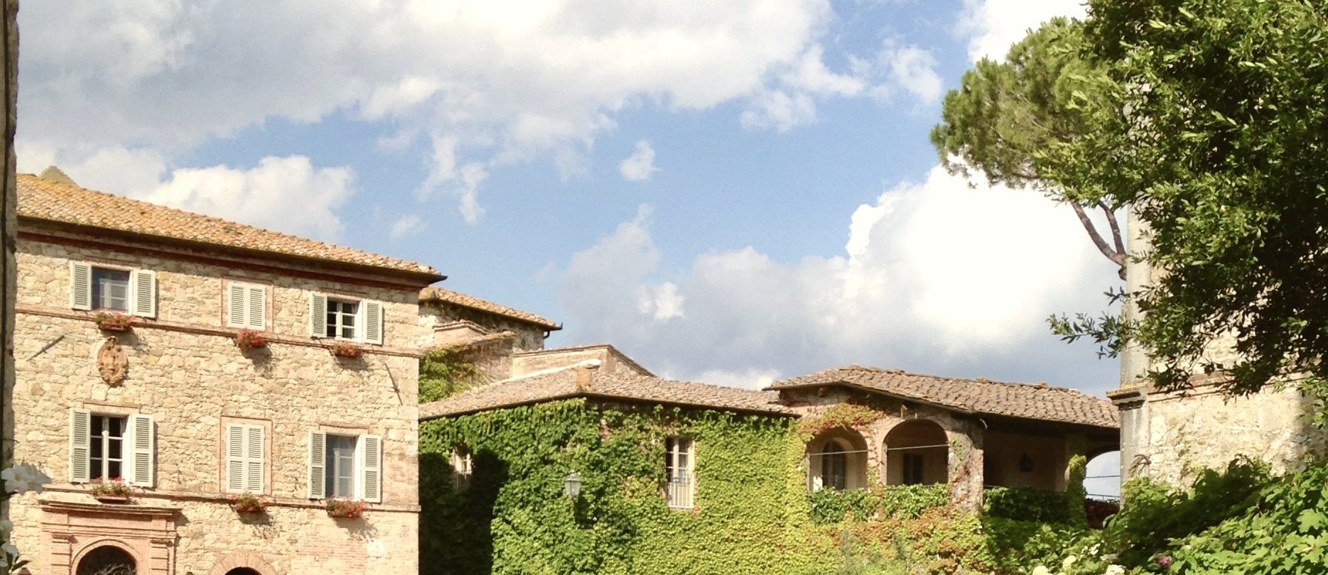 A stone villa wrapped in climbing ivy, warm afternoon light across the facade and an arched doorway standing open.